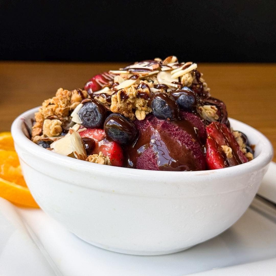 Açaí bowl topped with mixed berries, granola, sliced almonds and honey