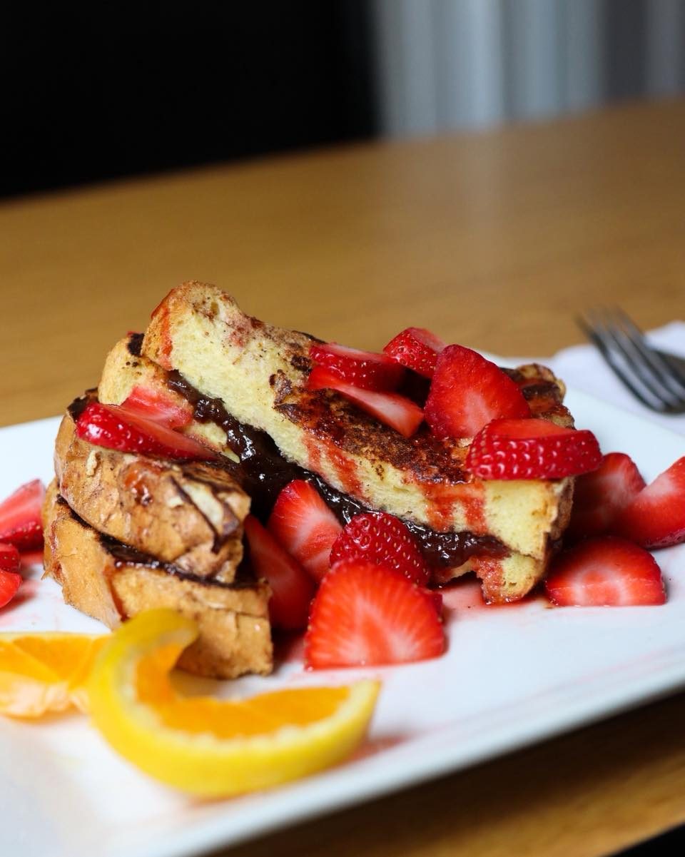 Thick-cut French toast piled with fresh strawberries and orange slices