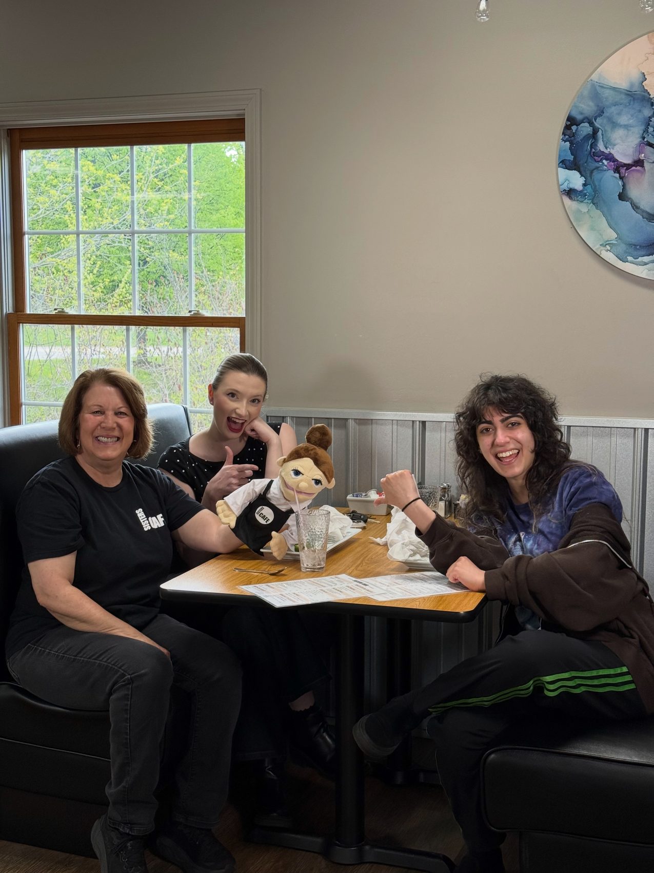 Members of the Sisters Cafe team laughing together in a booth in the dining room